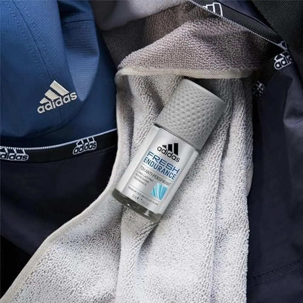 ADIDAS Fresh Endurance Roll-On Antiperspirant 50ml placed on a towel beside sporty apparel for maximum freshness.